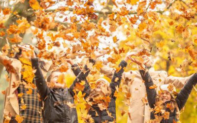 Family Throwing Leaves In October Half Term In Cornwall